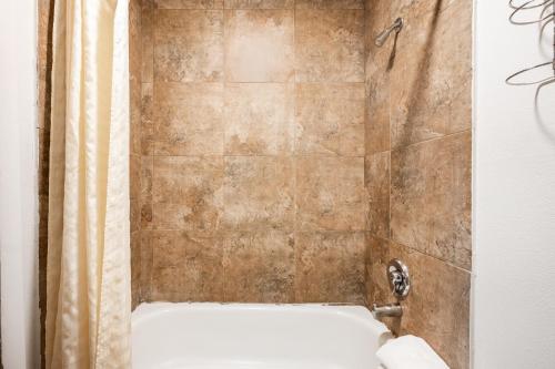 La salle de bains est pourvue d'une douche et d'un mur carrelé. dans l'établissement City Creek Inn & Suites, à Salt Lake City