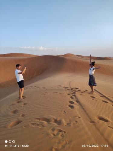 two people standing in the sand in the desert at SandGlass Camp in Bidiyah