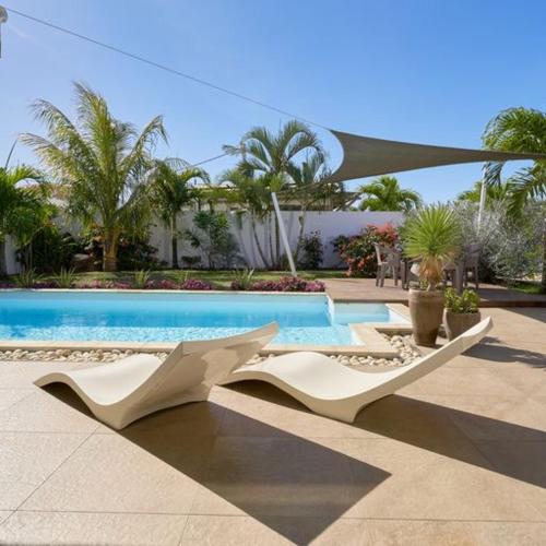 Villa Primera 3 bedroom bungalow with private pool Grand Bay في غراند بايَ: وجود مسبح مع كرسيي صالة بيضاء بجواره