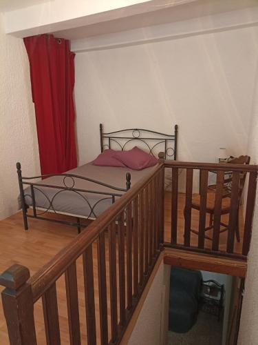 a bedroom with a bed and a staircase with a red curtain at Duplex meublé Mercantour in Fontan