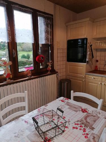 - une cuisine avec une table et des fleurs dans l'établissement Les Vosges ça vous tente ?, à Saint-Nabord