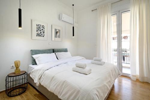 a white bedroom with a large bed with towels on it at Athens Delight Apartment in Pagrati in Athens