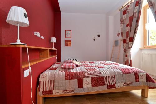 a bedroom with a bed and a red wall at S'Harzala Rouge in Bergheim