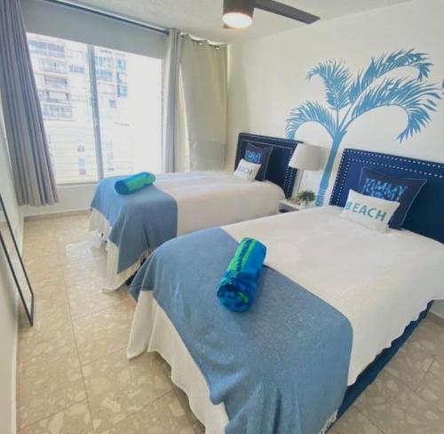 Habitación de hotel con 2 camas y una palmera en la pared en KASA Royal Palms, en San Juan