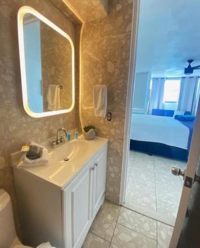 a bathroom with a sink and a mirror and a bed at Pool Beachfront 2 bedroom Condado Beach in San Juan