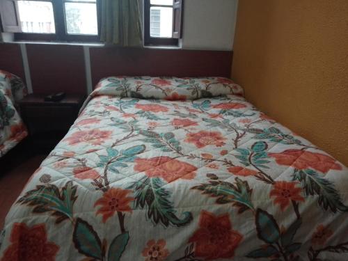 - un lit avec une couette à fleurs dans une chambre dans l'établissement Hotel El Dorado La Candelaria, à Bogotá