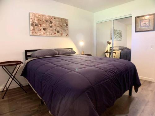 1 dormitorio con 1 cama grande con manta morada en Perfect Palm Springs Pied-à-terre en Palm Springs