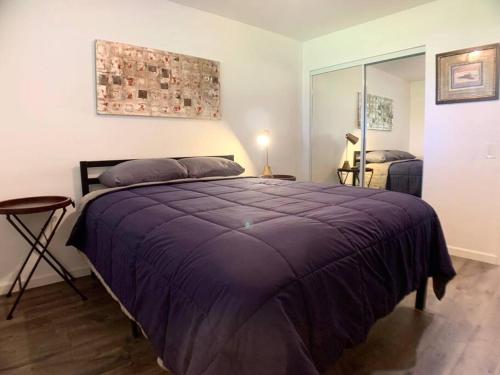 a bedroom with a large bed with a purple blanket at Perfect Palm Springs Pied-à-terre in Palm Springs