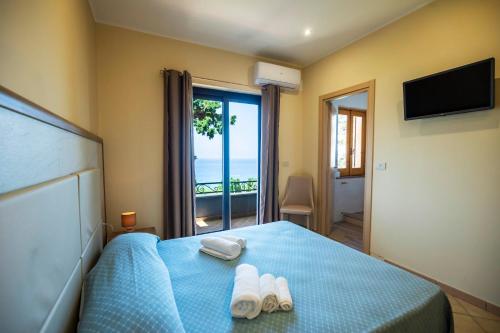 Un dormitorio con una cama azul con toallas y una ventana en Hotel La Fattoria Sul Mare, en Capo Vaticano