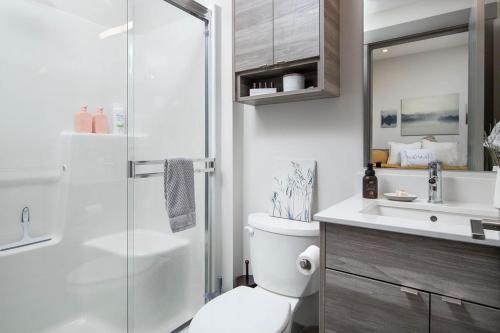 a bathroom with a shower and a toilet and a sink at Top Floor on Okanagan Lake with AC & Heated Pool in Vernon