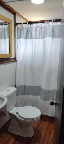 a bathroom with a toilet and a shower curtain at Refugio Los Cipreses Hotel in Futaleufú