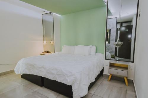 a bedroom with a large white bed and a mirror at Hotel Florencia Poza Rica in Poza Rica de Hidalgo