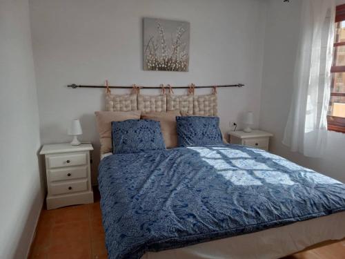 una camera da letto con un letto con piumone blu e due comodini di Ocean Breeze Albatros a San Miguel de Abona