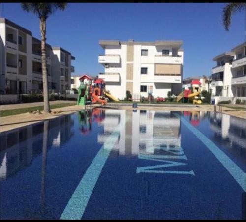 une piscine d'eau en face d'un bâtiment dans l'établissement Mohammédia Marbella beach appartement familliale, à Minaret de Mansuria