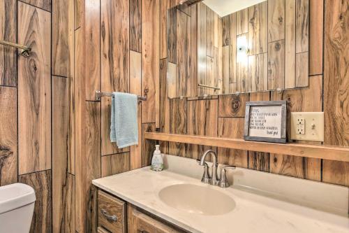 a bathroom with wooden walls and a sink and a mirror at Retro Rhinelander Lake Retreat with Fire Pit! in Rhinelander