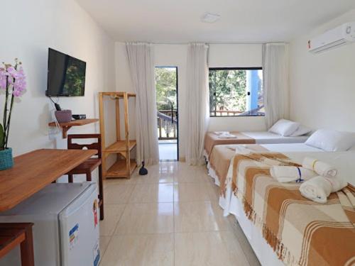 1 dormitorio con 2 camas, escritorio y TV en APARTAMENTOS DO BRUNO, en Arraial d'Ajuda