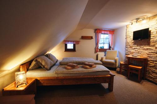 a bedroom with a bed and a chair and a television at Pension & Restaurant Krakonoš in Harrachov