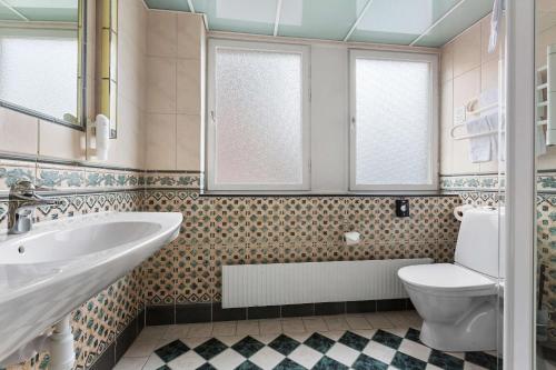 a bathroom with a sink and a toilet and windows at Best Western Kom Hotel Stockholm in Stockholm