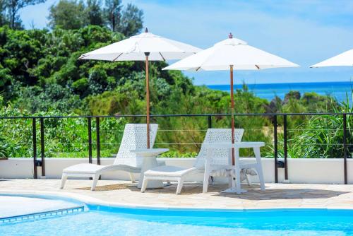 a pool with two chairs and a table and umbrellas at Best Western Okinawa Onna Beach in Onna