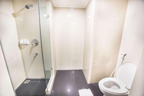 a bathroom with a toilet and a glass shower at Best Western Papilio Hotel in Surabaya