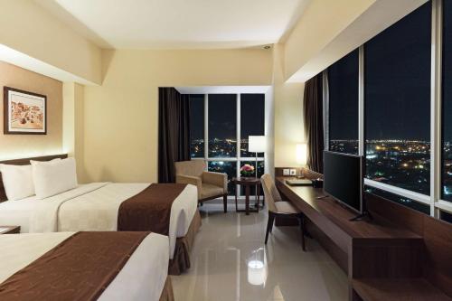 a hotel room with two beds and a desk at Best Western Papilio Hotel in Surabaya