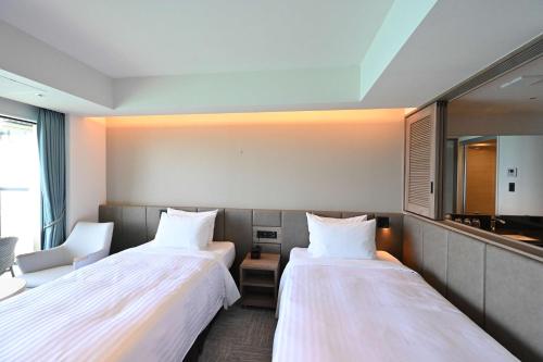 a hotel room with two beds and a mirror at Best Western Okinawa Kouki Beach in Nago