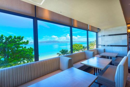 a restaurant with tables and a view of the ocean at Best Western Okinawa Kouki Beach in Nago