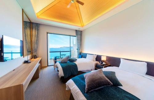 名護市にあるベストウェスタン沖縄幸喜ビーチのベッド2台と大きな窓が備わるホテルルームです。