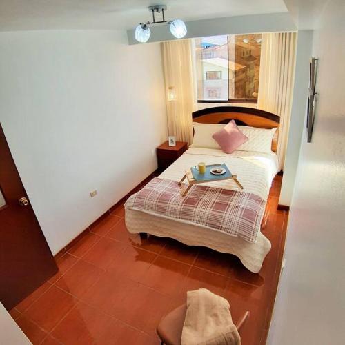 a bedroom with a bed with a table on it at Departamento para 6 personas a 3 minutos del aeropuerto in Cusco