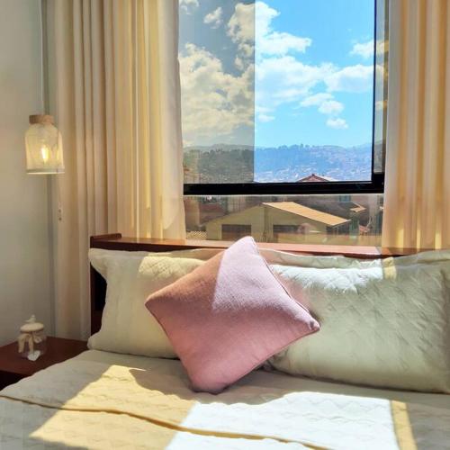 a bed with pillows and a window with a view at Departamento para 6 personas a 3 minutos del aeropuerto in Cusco