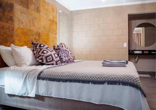 a bedroom with a bed with pillows and a mirror at Reserva do Paiva suites in Cabo de Santo Agostinho