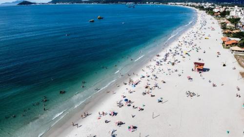 a group of people on a beach with the ocean at Pousada Roberto Monteiro - Frente Mar in Florianópolis