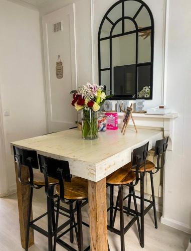 une table à manger avec des chaises et un vase de fleurs dans l'établissement La Maison Du Bois Flotté, à Boulogne-sur-Mer