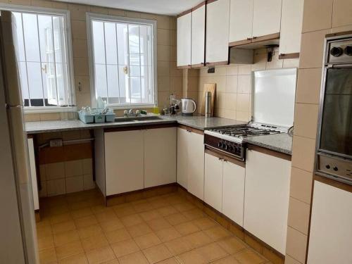 uma cozinha com armários brancos e um forno com placa de fogão em Casa Chill em Mendoza