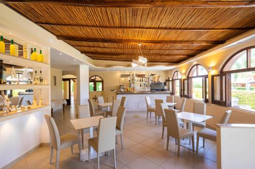 a restaurant with tables and chairs and a kitchen at Hotel La Fattoria Sul Mare in Capo Vaticano