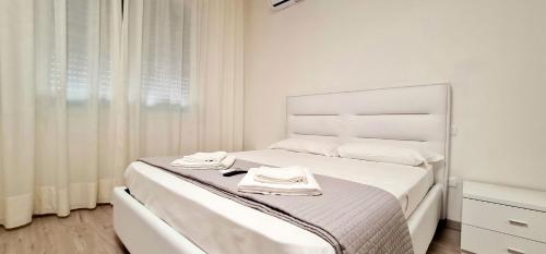 a white bedroom with a bed with two towels on it at Farah’s house in Padova