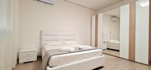 a white bedroom with a bed and a mirror at Farah’s house in Padova