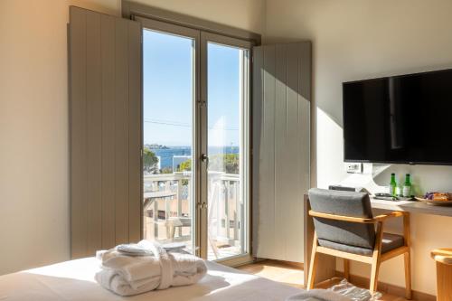 una camera d'albergo con letto, scrivania e finestra di Fabrikas a Mykonos Città