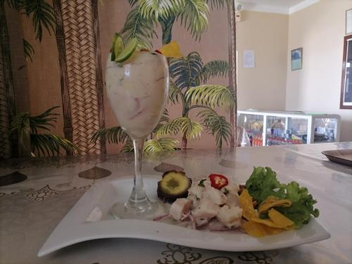 un plato con una bebida y una ensalada en una mesa en Hospedaje Restaurante El Hombre, en Puerto Chicama