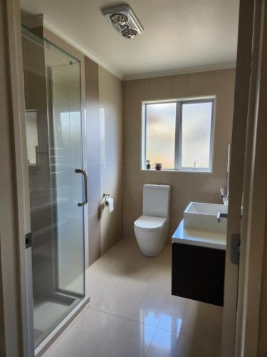 a bathroom with a toilet and a sink and a shower at Sweet home in Albany in Auckland