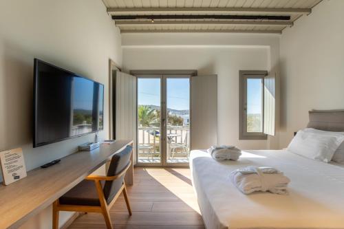 een slaapkamer met een bed en een bureau met een flatscreen-tv bij Fabrikas in Mykonos-stad