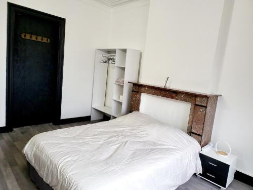 a bedroom with a white bed and a black door at Private industrial room in center of Charleroi in Charleroi