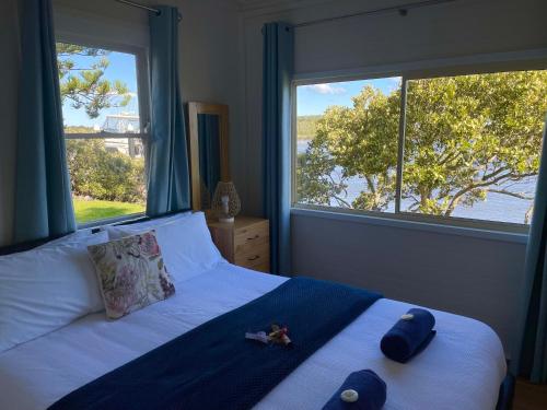 a bedroom with a bed with two large windows at Waterfront Cottages in Greenwell Point