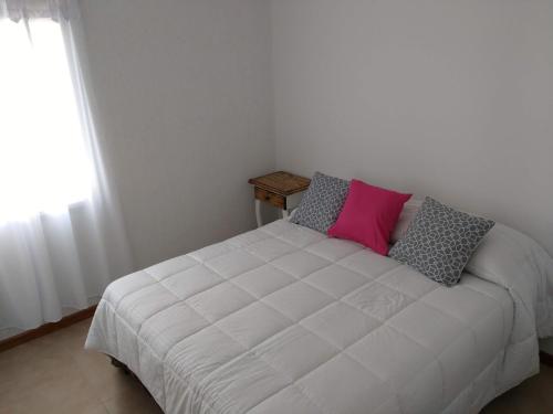 Un dormitorio con una cama blanca con almohadas y una ventana en Hermoso Departamento en Mendoza en Mendoza