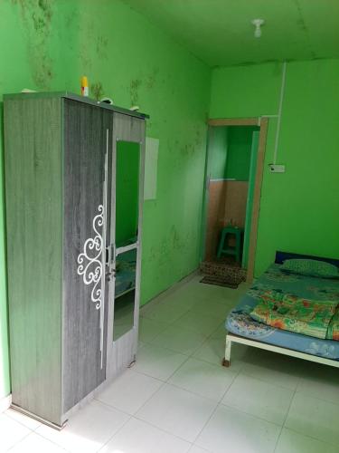 Habitación verde con cama y puerta. en WisPing, en Tanjung Pinang