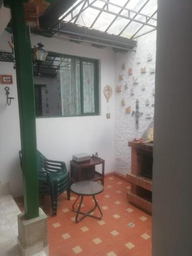 a room with a green chair and a table and a piano at Hotel Boutique La Cueva de la Luna, El Arte se hace Descanso in Duitama
