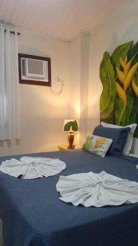 a bedroom with a blue bed with two shirts on it at La Coloniale in Búzios