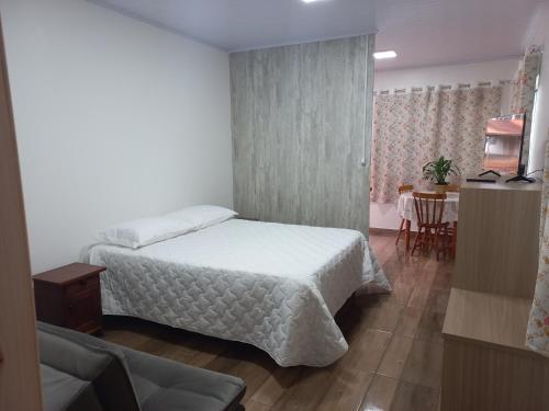 a bedroom with a white bed and a table at Hospedaria Mitterer in Treze Tílias