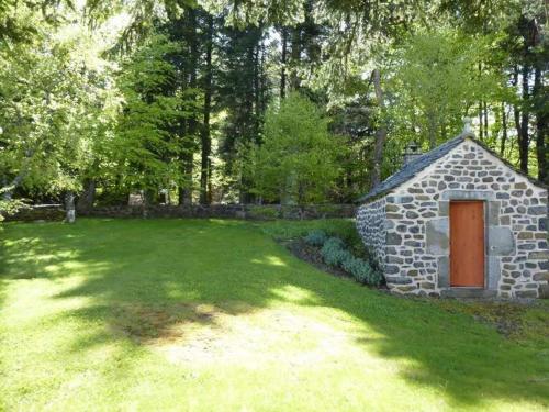 a small stone building with a brown door in a yard at Maison en forêt avec terrasse, jeux pour enfants et cheminée, près du Pic du Lizieux et du Lac bleu - FR-1-582-235 in Araules