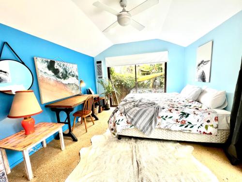 a bedroom with blue walls and a bed and a desk at Entire Blaxland Cottage in Blaxland